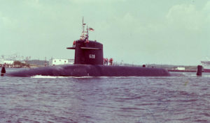 Submarine USS Tecumseh pulling into port with sailors on the sail and deck