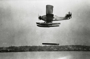 An historic aircraft drops a torpedo towards the water