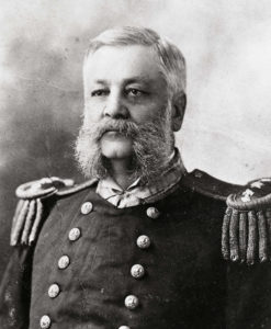A 19th century portrait photograph of a middle aged man with large mutton chops in a Navy uniform