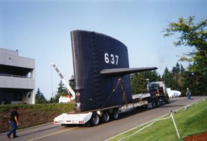 Detached submarine sail traveling on flatbed truck up the museum driveway