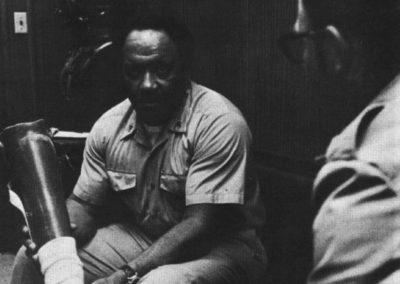 Carl Brashear holds a prosthetic leg as he talks to another Sailor.