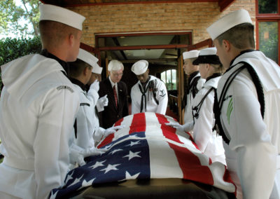 Sailors carry a casket draped with an American flag.