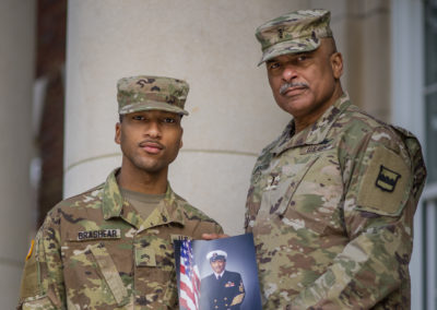 Phillip Brashear and his son Tyler wear Army uniforms. Phillip holds a photograph of his father, Carl Brashear.