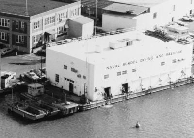 Aerial view of the Naval School of Diving and Salvage, a boxy white building next to water.