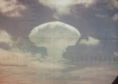 A white mushroom cloud is viewed through a sight.