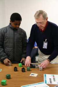Image shows museum volunteer engaging a young learner with programmable cubes during an education program.