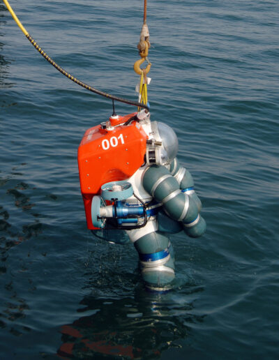 An atmospheric diving suit is lowered into water.
