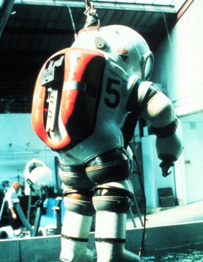 An atmospheric diving suit is lowered into the water.