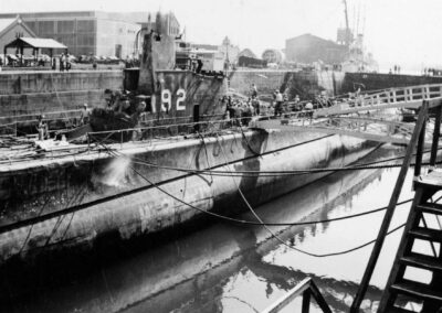 Submarine USS Squalus sits in dry dock as people mill on its deck.