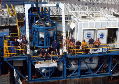Divers flank a white and blue saturation diving system.