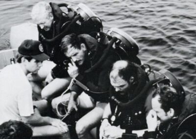 A group of Special Operations Forces divers wear Mark 15 rebreathers on their backs while sitting in a small boat.